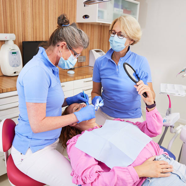 Zahnarzt und Zahnarzthelferin mit einem Patienten
